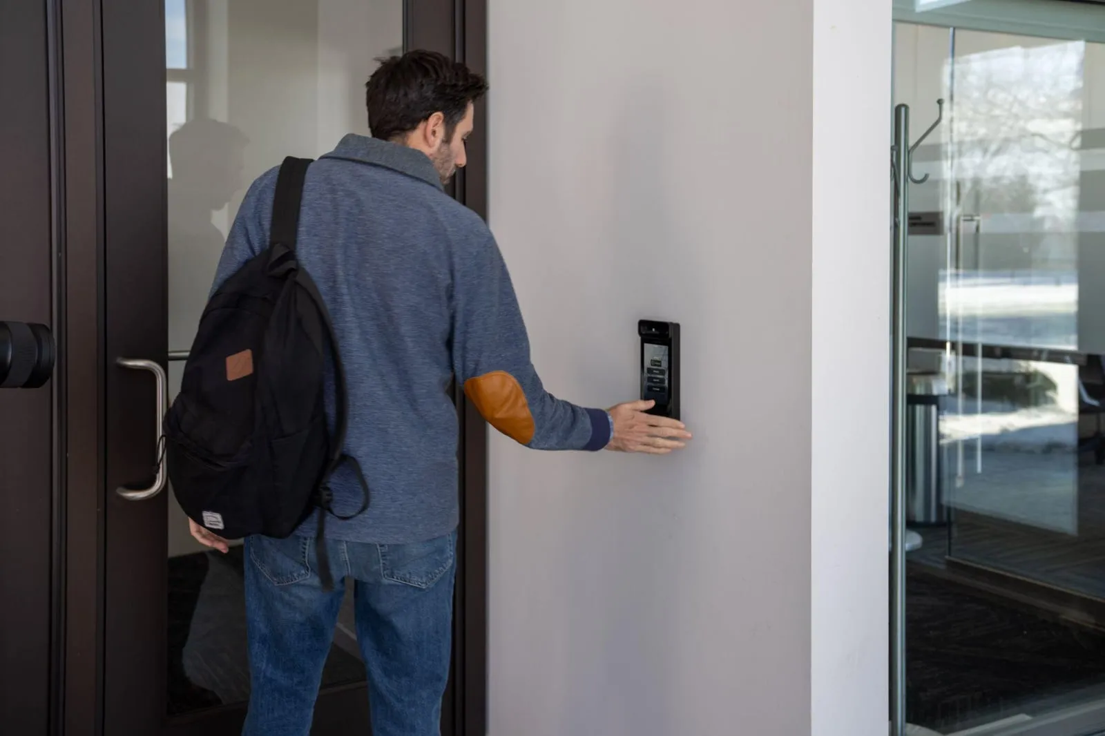 A man waves his hand in front of Intercom Touch to open the door